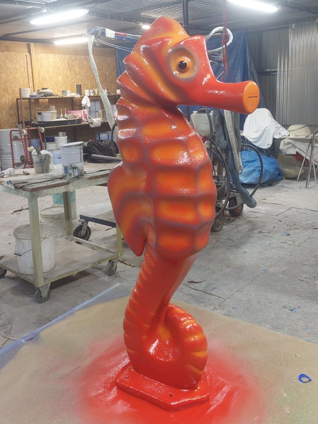 Sculpture d'un hippocampe orange en position verticale.