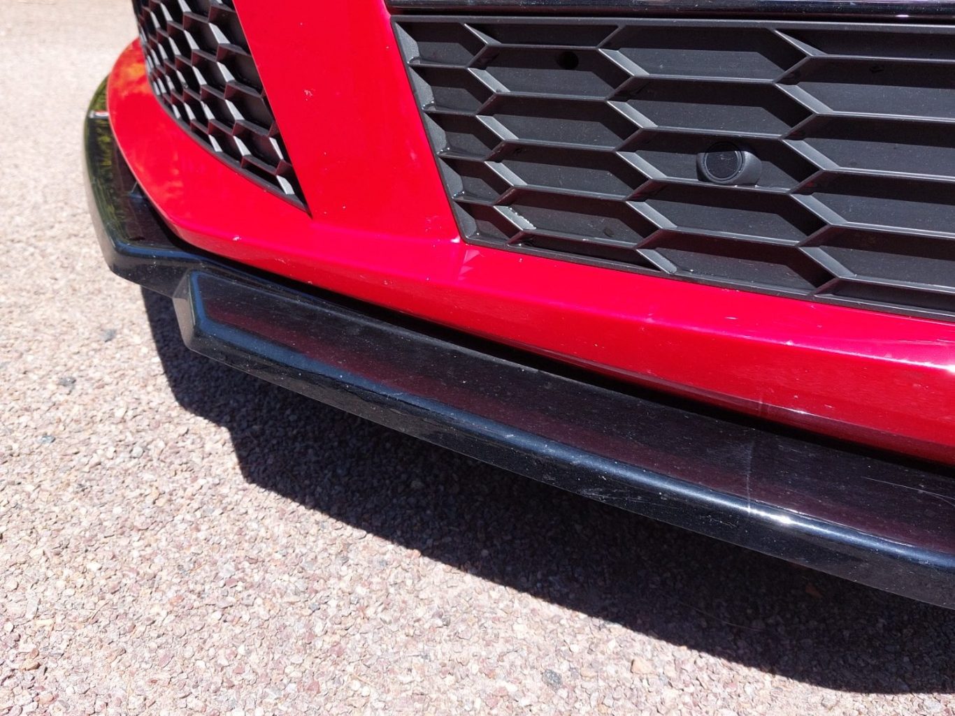 lame spoiler voiture de sport Partie inférieure d'un pare-chocs de voiture rouge, vue de près avec des détails noirs.