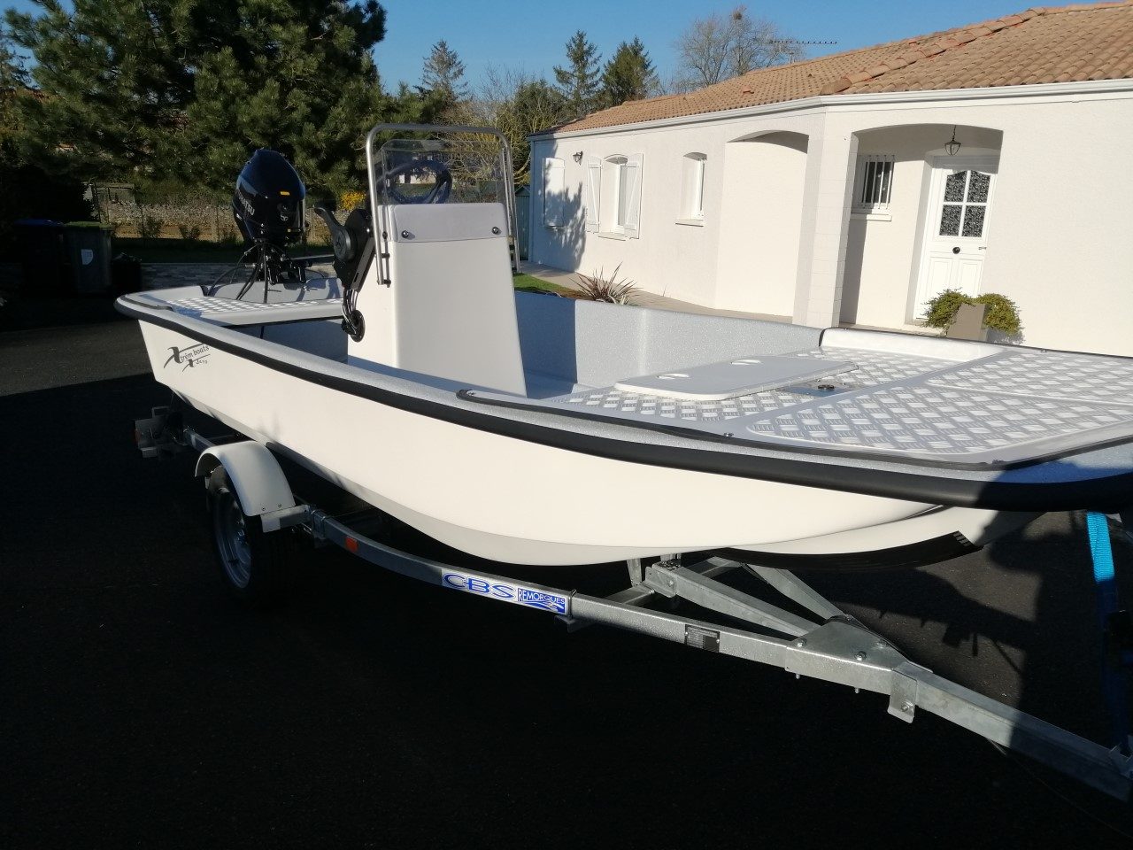 barque XJ410 fabriquée exclusivement dans notre atelier Bateau à moteur blanc sur remorque, garé près d'une maison.