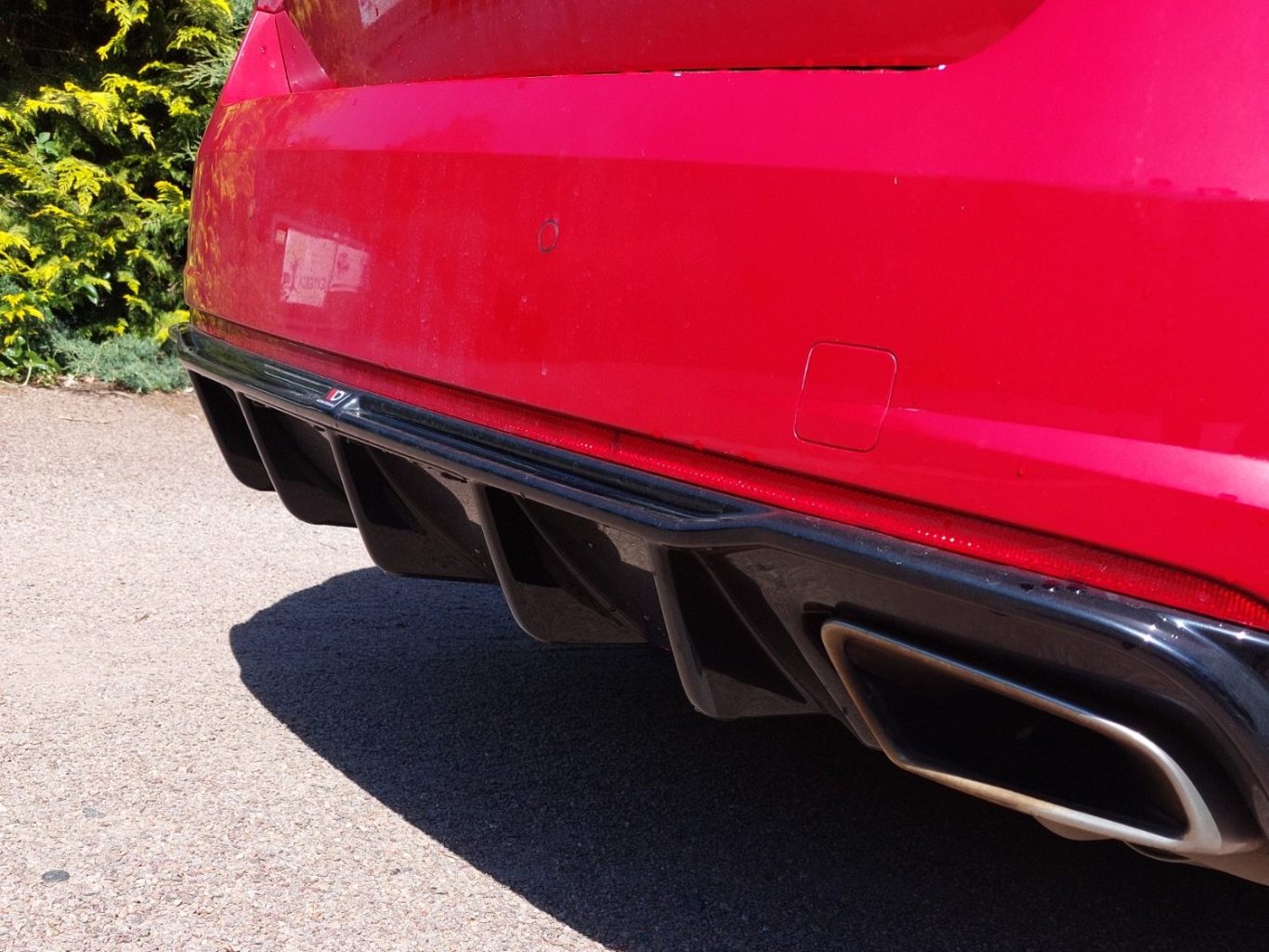 Peinture et vernis sur spoiler voiture Détail d'un pot d'échappement d'une voiture rouge avec une finition noire.