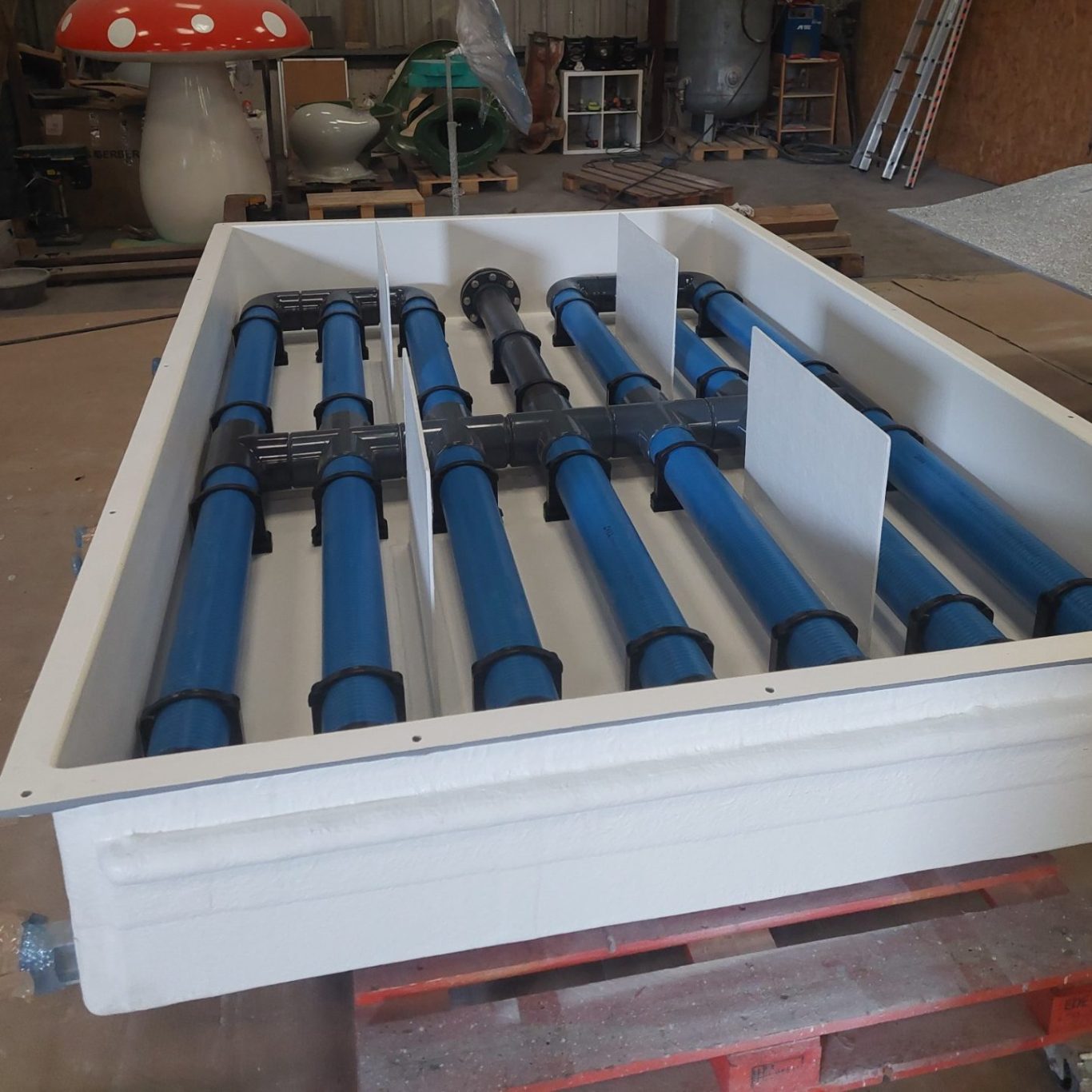 Réservoir blanc avec des tubes bleus pour le transport de fluides.
