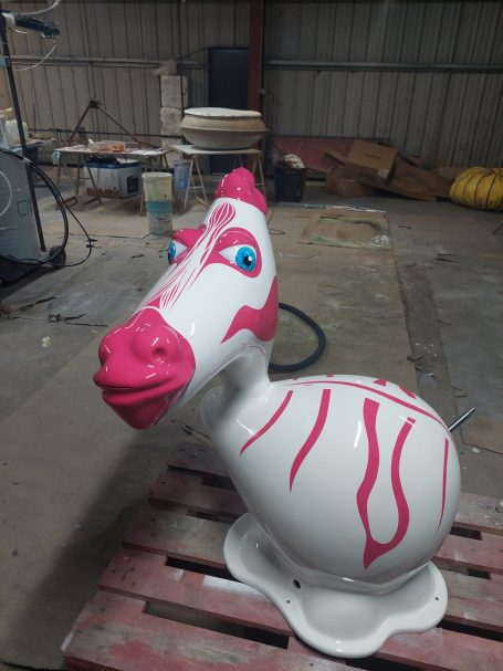 Sculpture d'un cheval en plastique avec des rayures roses et un sourire.
