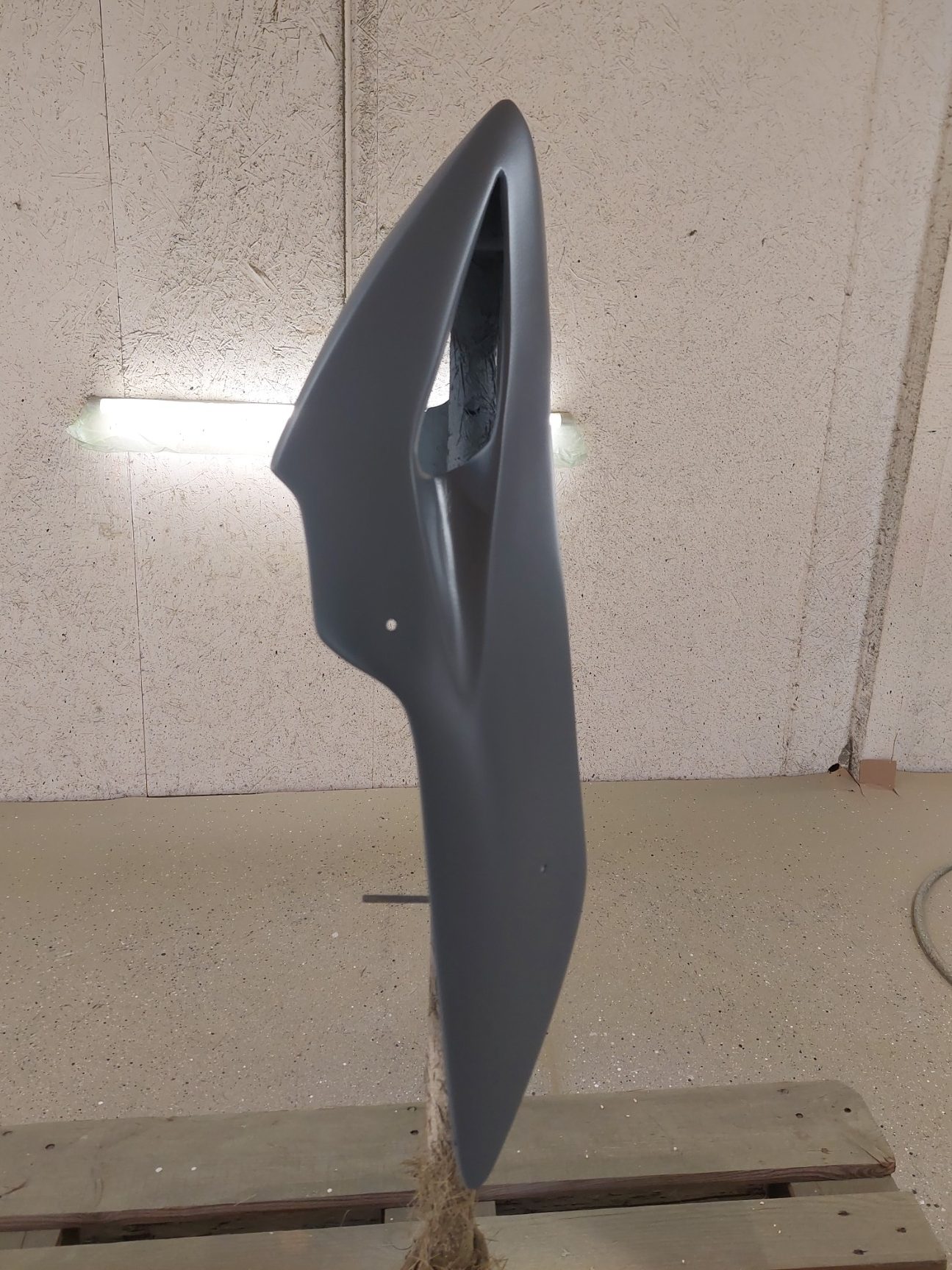 Pièce de carrosserie grise, profil aérodynamique, fond neutre.