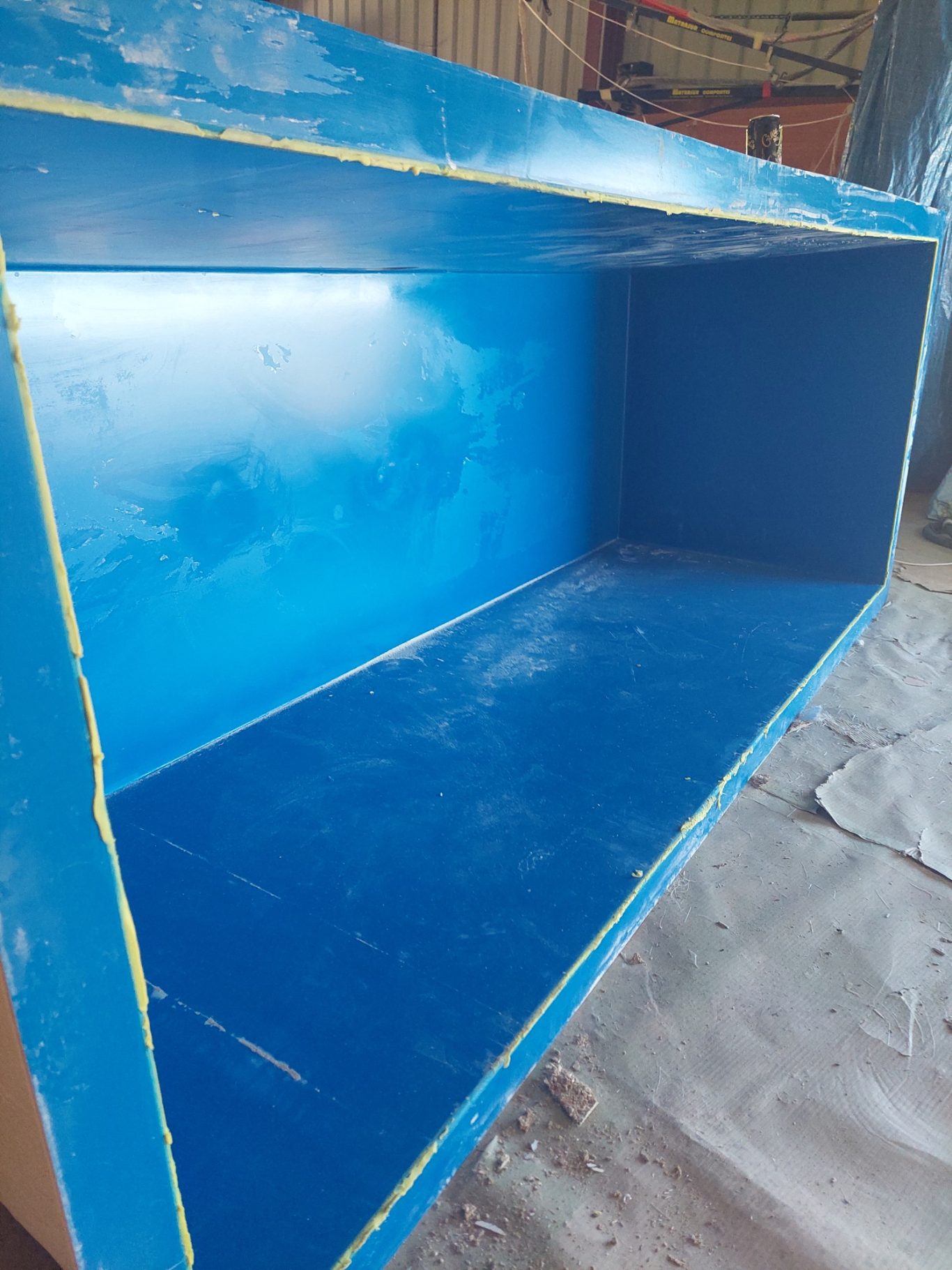 bac à nurserie pour les huitres Boîte bleue vide avec des bords jaunes, sur un fond de surface de travail.