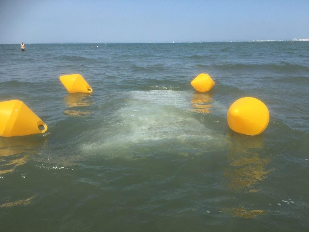 système de filtration d'eau de mer partiellement immergé entouré de bouées jaunes dans l'eau.