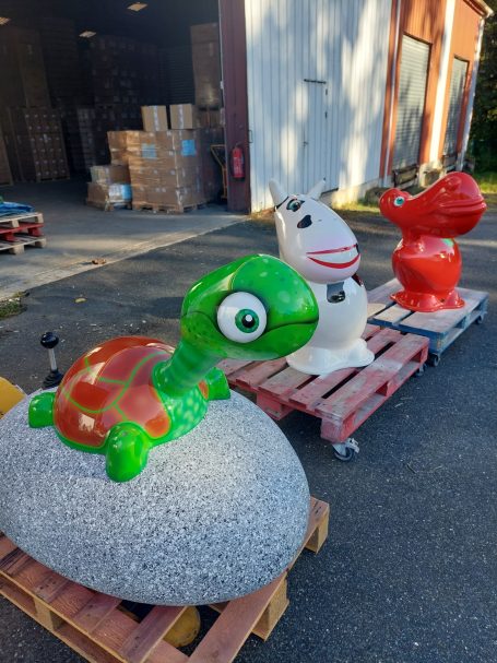 Tortue verte sur un rocher, un cheval blanc et un oiseau rouge en décoration extérieure.